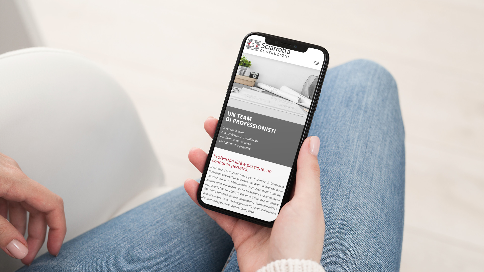 Mano con iPhone che mostra il sito web in modalità mobile responsive di Sciarretta Costruzioni di Teramo