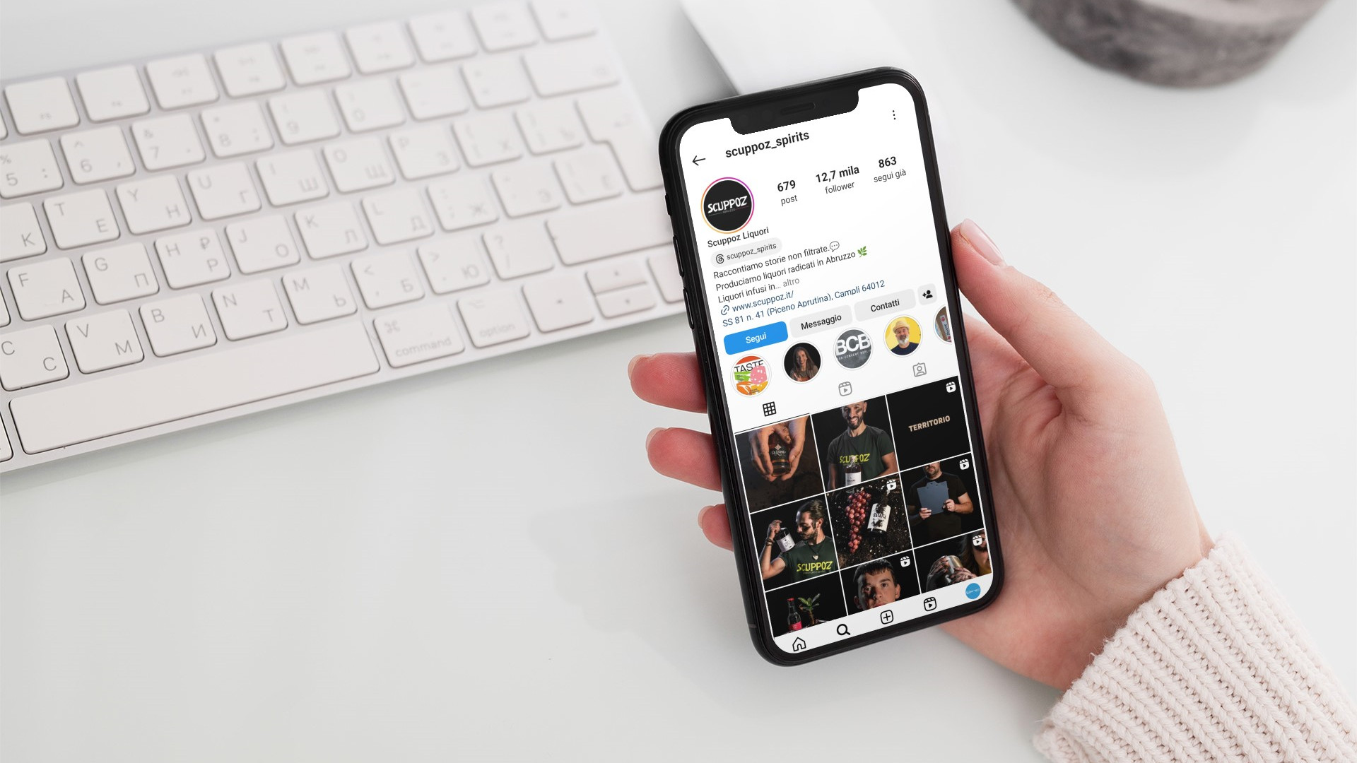 Ragazza che guarda la pagina Instagram di Scuppoz liquori a Teramo in Abruzzo dal proprio iPhone sulla scrivania