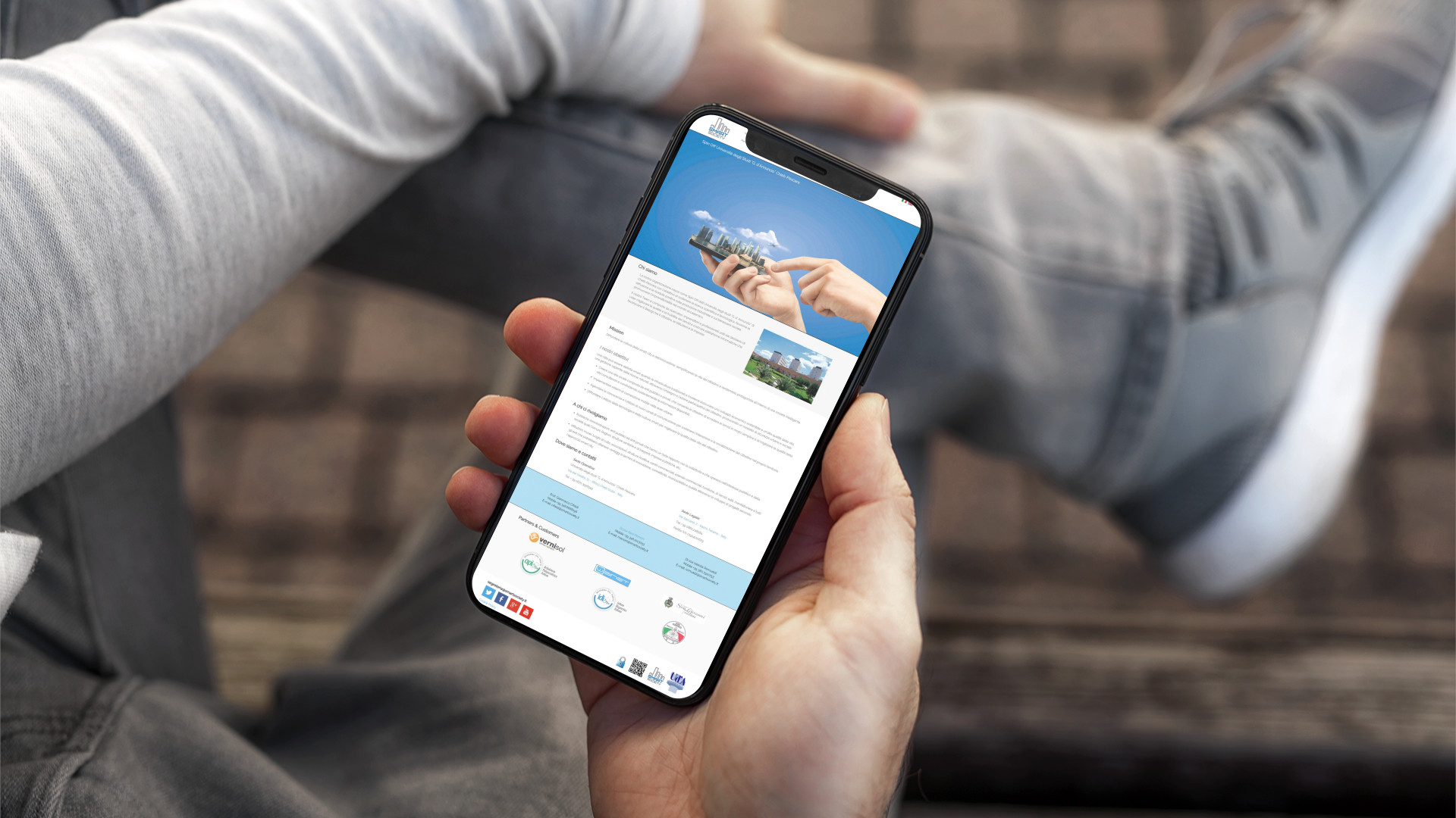 Mano con iPhone che mostra il sito web in modalità mobile responsive di Smart Society di Pescara