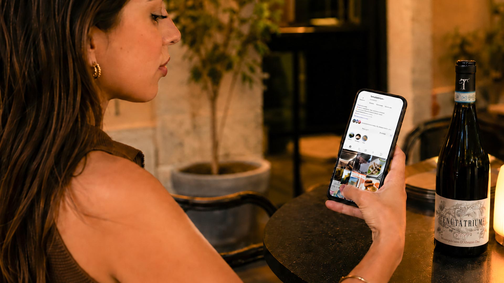 Ragazza con iPhone mentre guarda il profilo Instagram Tenuta Trium