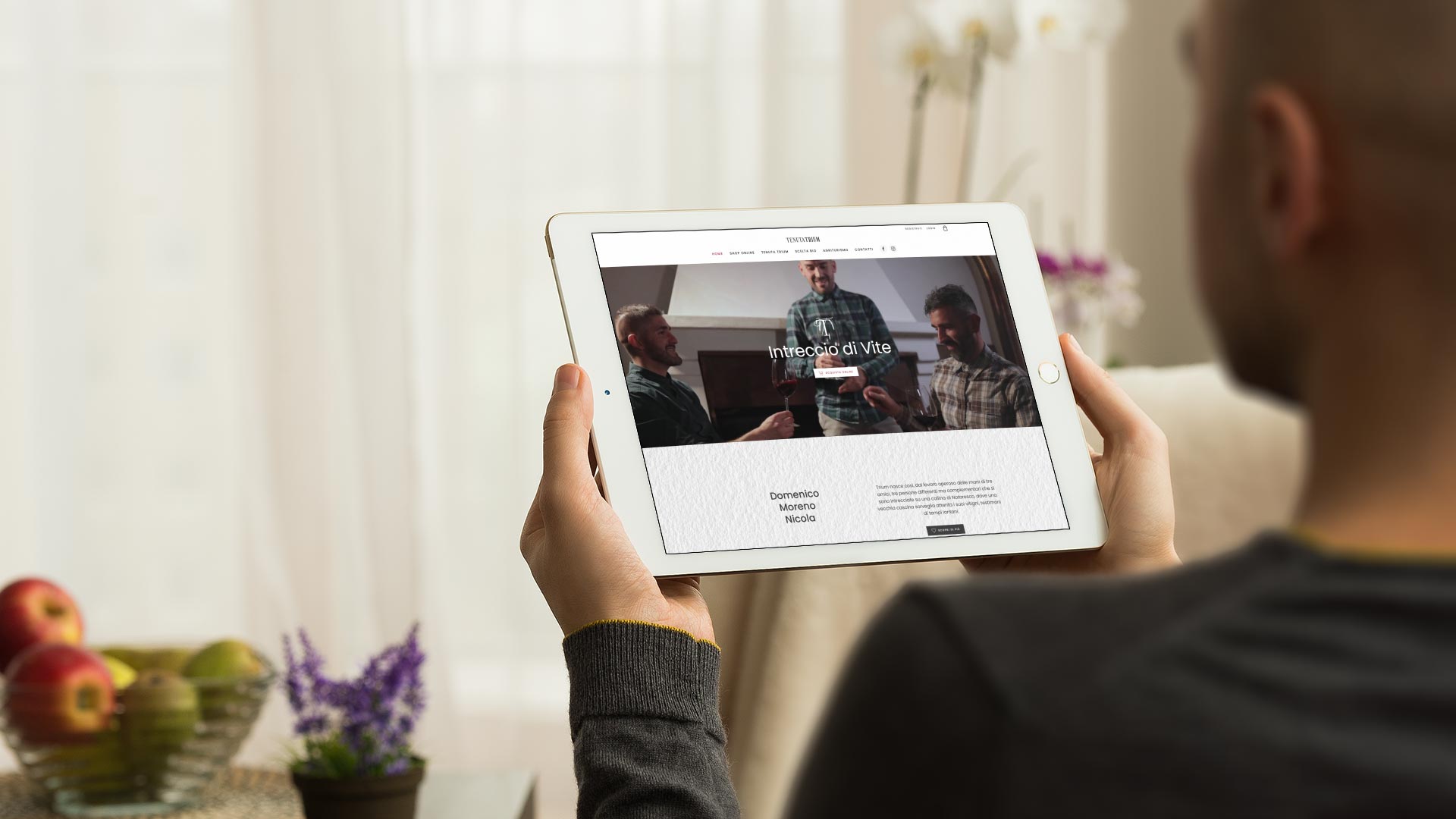 Uomo in salotto con iPad mini guarda Sito Web tenutatrium.it