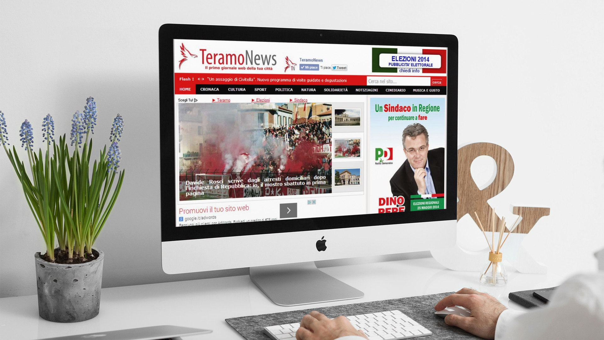 Uomo che guarda sull'iMac la home page del sito web di Teramo News