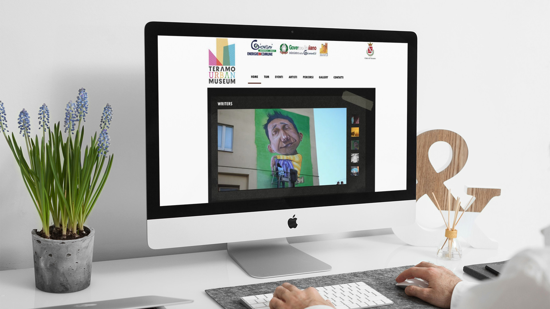 Uomo che guarda sull'iMac la home page del sito web di Teramo Urban Museum