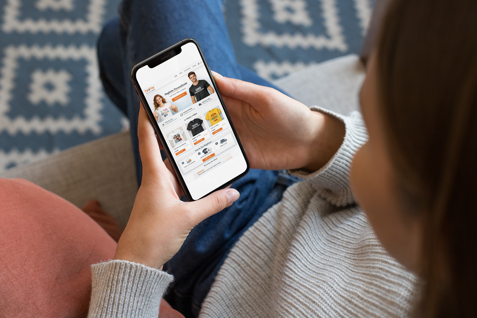 Ragazza seduta sul divano che guarda sullo smartphone la home page del Sito Web e-commerce Tip&Top