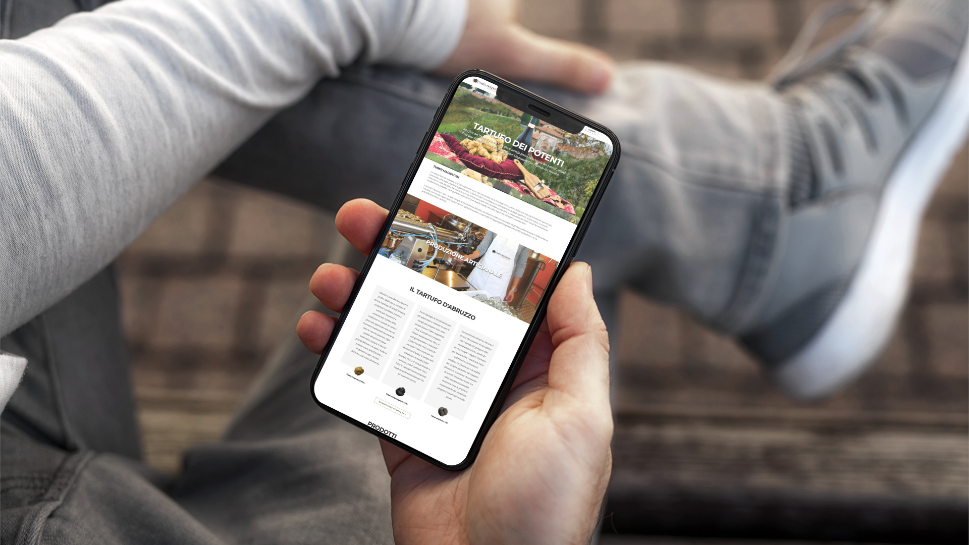 Mano con iPhone che mostra il sito web in modalità mobile responsive di Tuber Magnatum