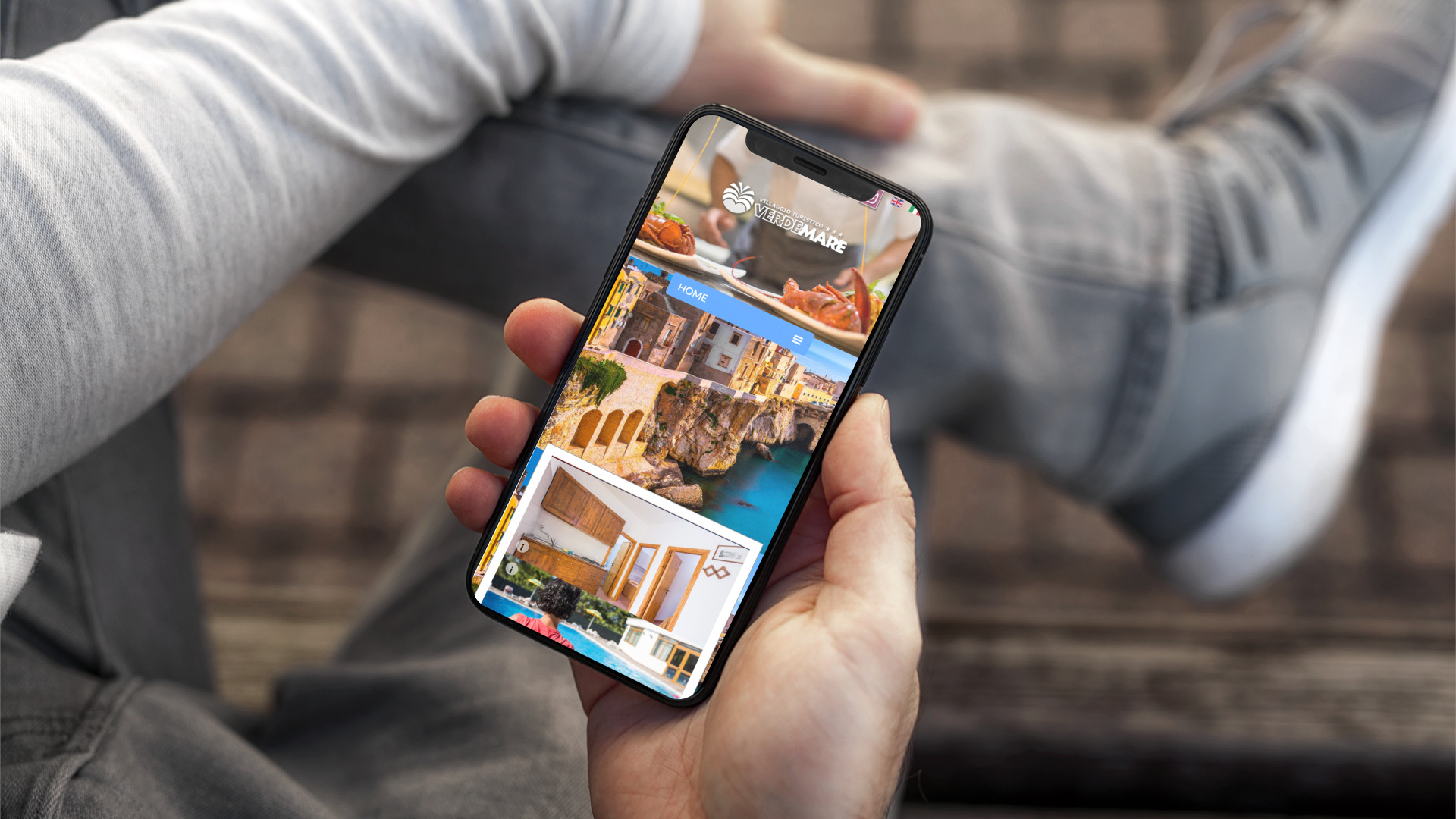Mano con iPhone che mostra il sito web in modalità mobile responsive del Villaggio Verdemare di Vieste