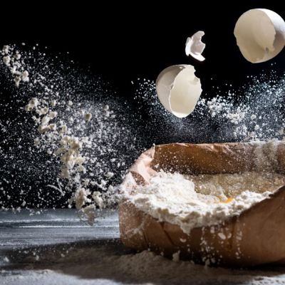 Uova e farina sospese sopra un sacchetto durante una composizione creativa