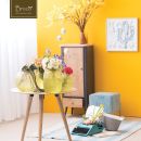 Angolo d'arredo giallo con mobile alto, fiori e tavolino