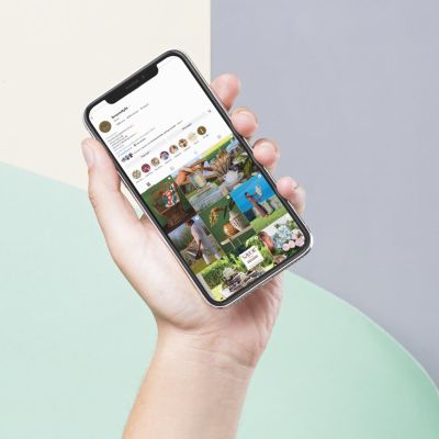 Mano che tiene uno smartphone con il feed Instagram di Bruco visualizzato sullo schermo