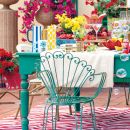 Tavola colorata all'aperto con fiori, sedie e oggetti decorativi
