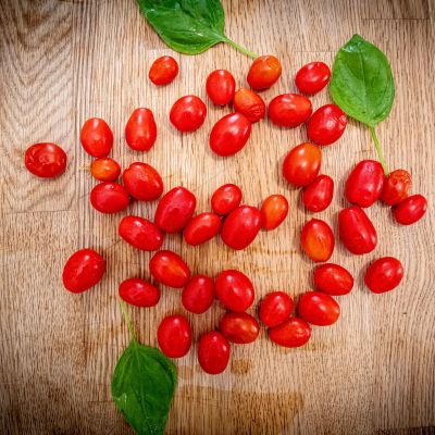 Pomodorini disposti a cuore con foglie di basilico