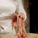 Cuoca mostra le fettuccine rosse appena tagliate