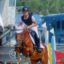 Amazzone su cavallo baio durante un salto in una gara equestre