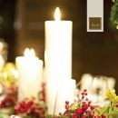 Candele bianche accese circondate da bacche rosse