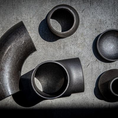 Curve, riduttori e fondelli in acciaio FENP disposti su una superficie scura