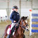 Bambina su un pony durante una gara equestre al coperto