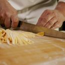 Taglio a mano delle fettuccine gialle sulla spianatoia