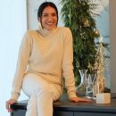 Donna sorridente seduta accanto a un albero di Natale