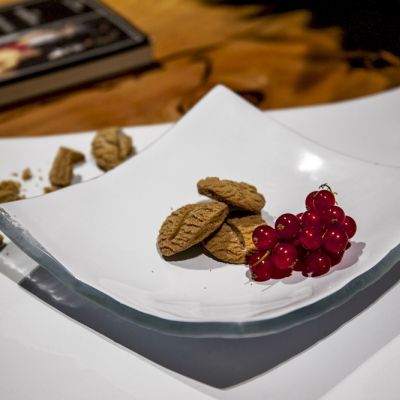 Piatto curvo in vetro bianco con biscotti e ribes rossi