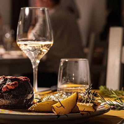 Piatto di carne con patate accompagnato da un calice di vino