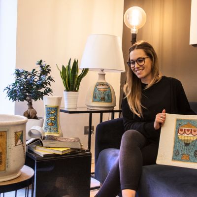Donna seduta sul divano mostra un piatto della collezione Terzo Cielo