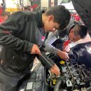 Due meccanici mentre lavorano nel vano motore di un'automobile