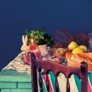 Still life di frutta e verdura su tavola apparecchiata con sfondo blu