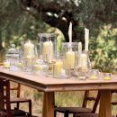 Tavolo in giardino apparecchiato con numerose candele