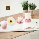 Quaderno aperto con candele rosa, margherita e piccoli vasi