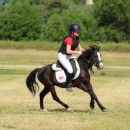 Bambino in gara con un pony nero su un campo in erba