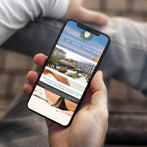 mano con Iphone che mostra il sito web in modalità mobile responsive de Hotel Marconi di Grottammare creato da Wainet Web Agency di Teramo