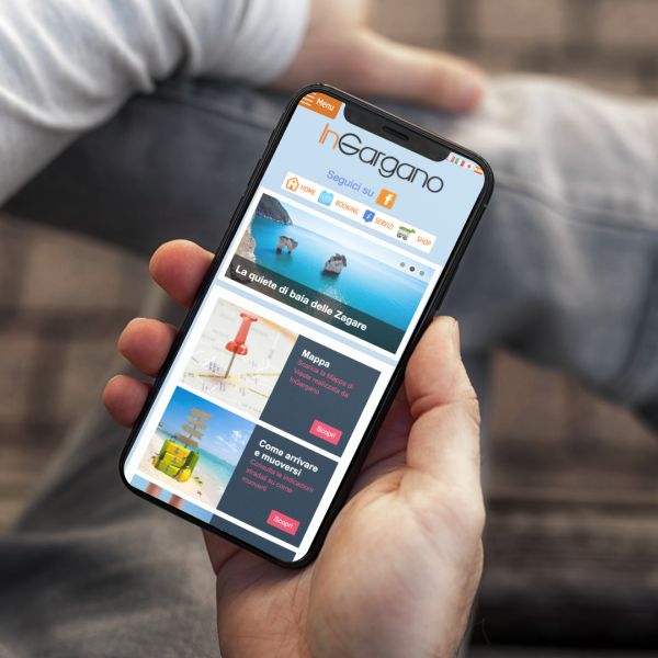 mano con Iphone che mostra il sito web in modalità mobile responsive di InGargano realizzato da Wainet Web Agency di Teramo
