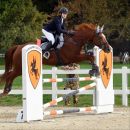 Amazzone durante il salto di un ostacolo decorato con teste di cavallo