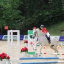 Amazzone con cavallo bianco durante un salto a ostacoli