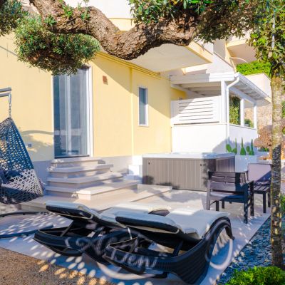 Patio della suite Orchidea con lettini, poltrona sospesa e ulivo