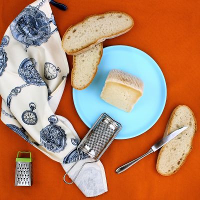 Pecorino abruzzese con pane e grattugia in uno still life su sfondo arancione