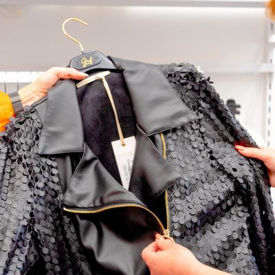 Giacca nera con paillettes e cintura mostrata su una gruccia