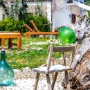 Ulivo con damigiane decorative e sedute nel giardino dello Shanti B&B