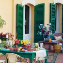 Tavolo colorato su un patio davanti a finestre con persiane verdi