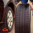 Addetto mentre sposta un pneumatico accanto a un'automobile