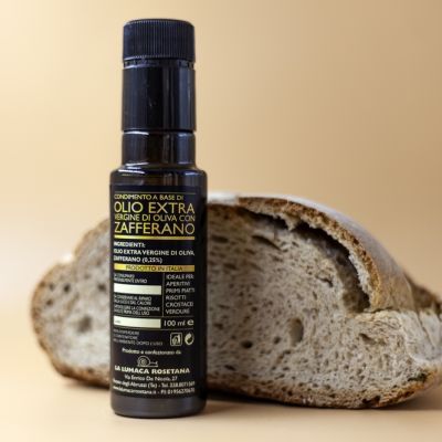 Bottiglia di olio extra allo zafferano accanto a una fetta di pane