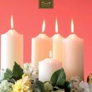 Candele color avorio circondate da fiori su sfondo corallo