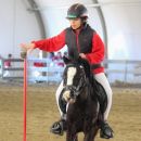 Bambina su un pony accanto all'istruttrice durante una prova