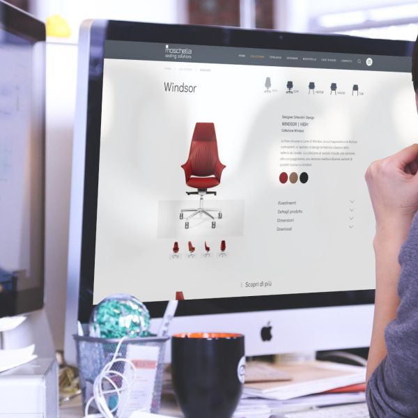 designer guarda imac con aperto sito web di moschella sedute di teramo