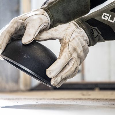 Operatore con guanti durante il controllo di un raccordo in acciaio