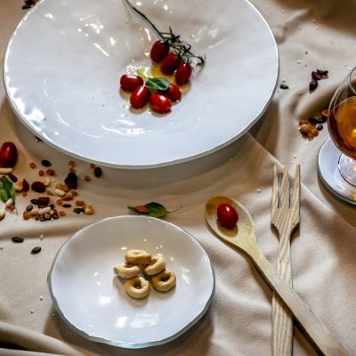 Piatti in vetro bianco apparecchiati con frutta, semi e bicchiere