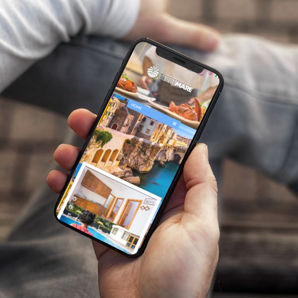 mano con Iphone che mostra il sito web in modalità mobile responsive del Villaggio Verdemare di Vieste
