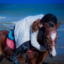 Bambina abbraccia il proprio pony sulla spiaggia