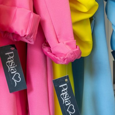 Abiti rosa, arancioni, gialli e azzurri con etichette del negozio