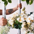 Braccio tatuato mentre regge una composizione di fiori bianchi